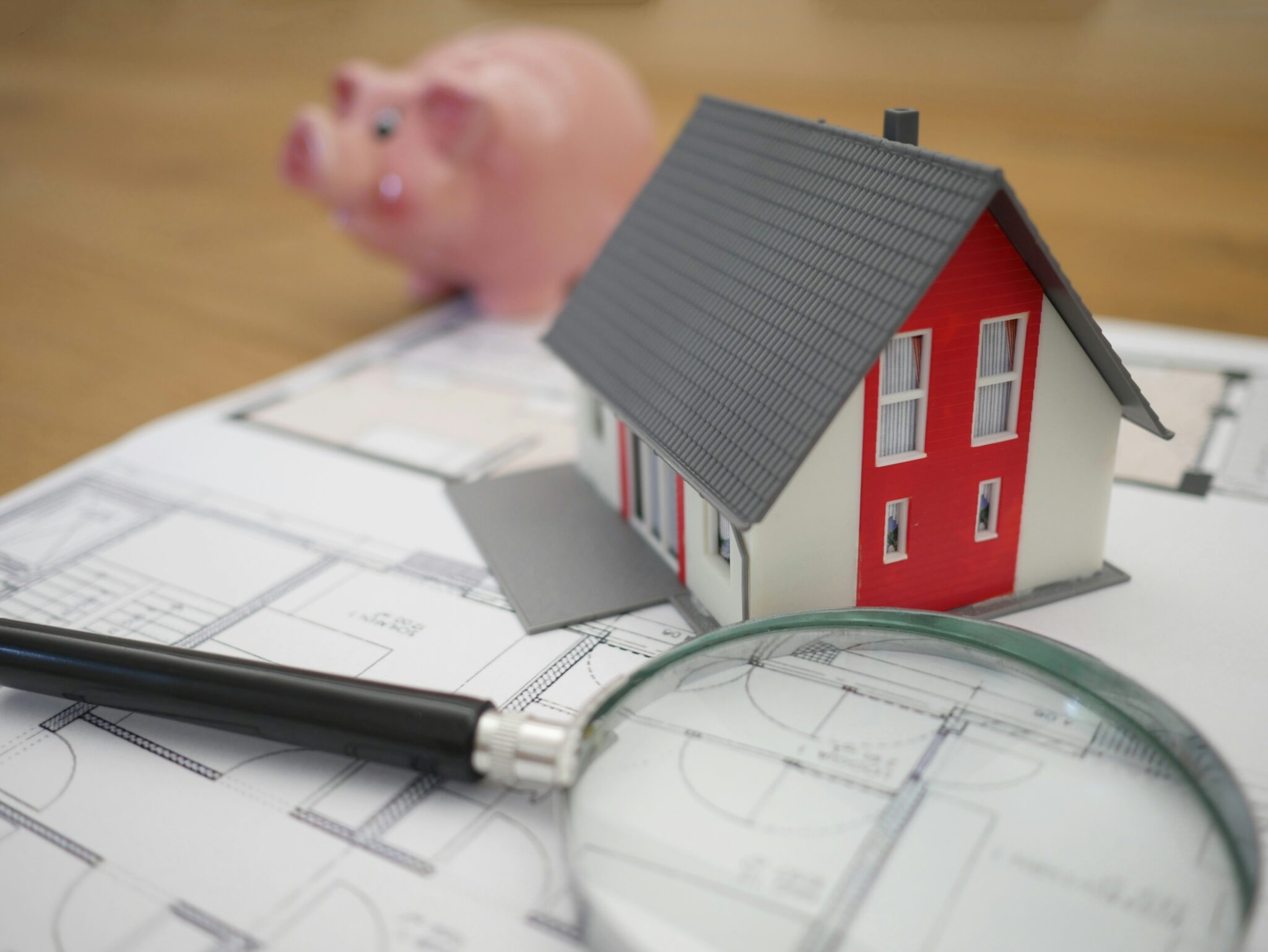 A magnifying glass and miniature house on a printed floor plan