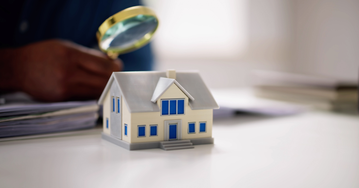 Home appraiser examining miniature house with magnifying glass