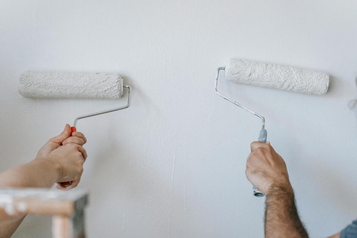 Two people painting a wall white