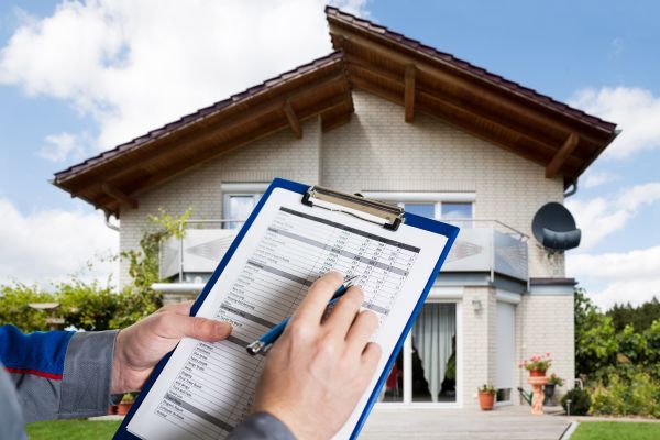 Residential appraiser inspecting home exterior outdoors